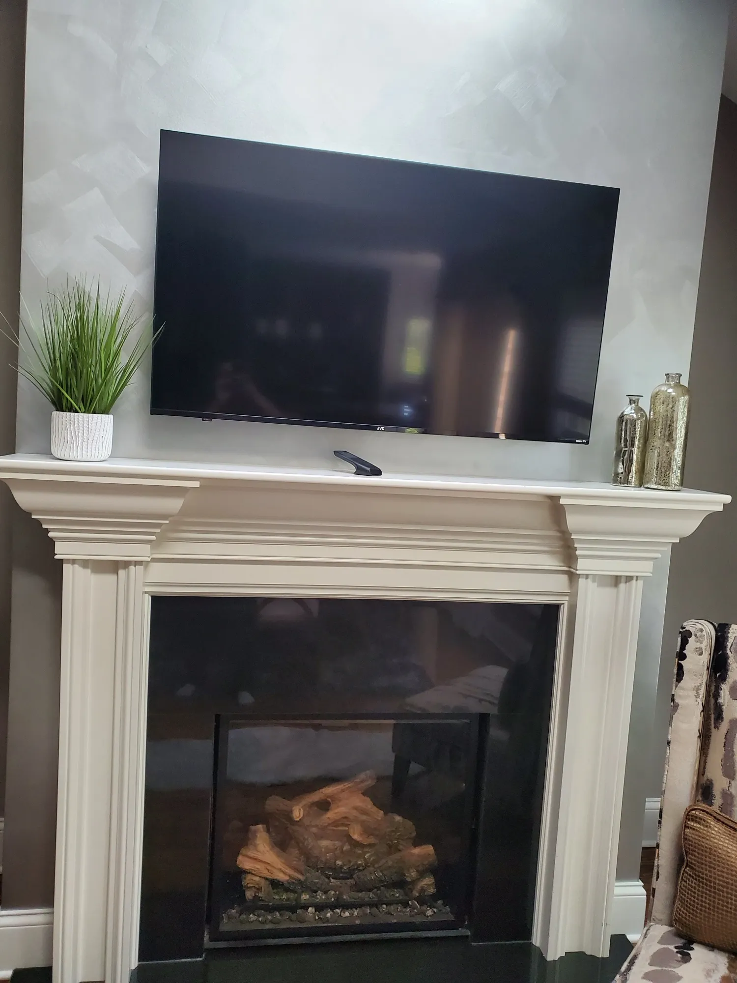 Television mounted above a traditional white painted mantel and gas fireplace.